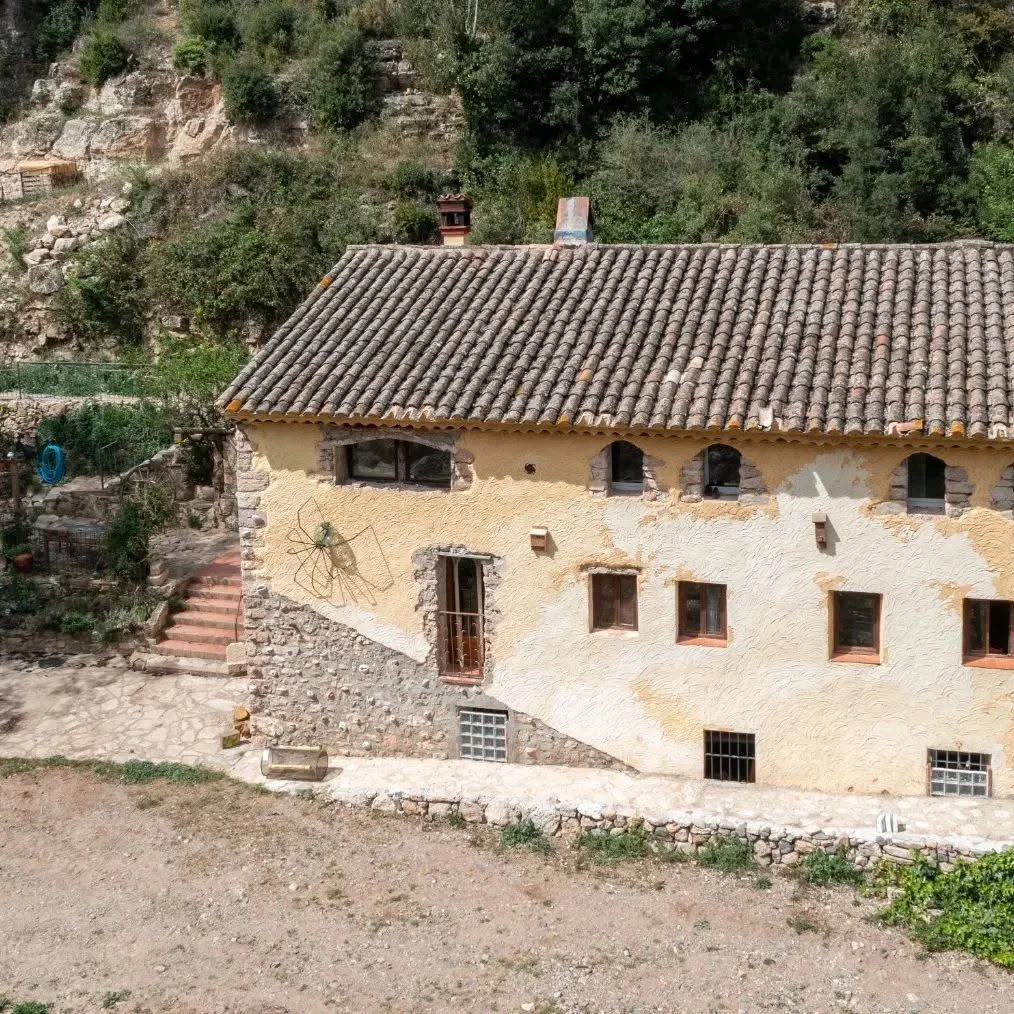 Molí del Fort Façana de pedra i teulada de teules del Molí del Fort, al costat d’un vessant arbrat.