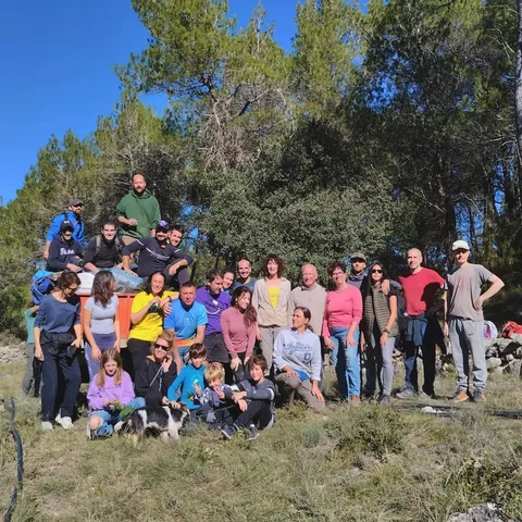 Un grup d’adults i infants posa en un entorn de bosc i roques.